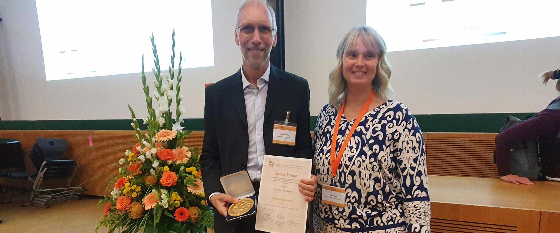 Dr. Dieter Martens and Dr. Anja Töpper in front of a flower arrangement
